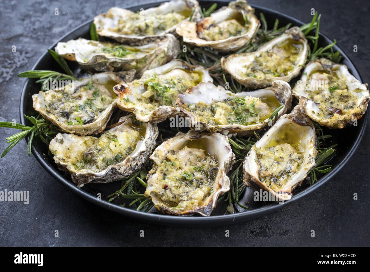 Grill overbaked frische Austern mit Knoblauch und Kräuter als Closeup auf einem Tablett Angeboten geöffnet Stockfoto