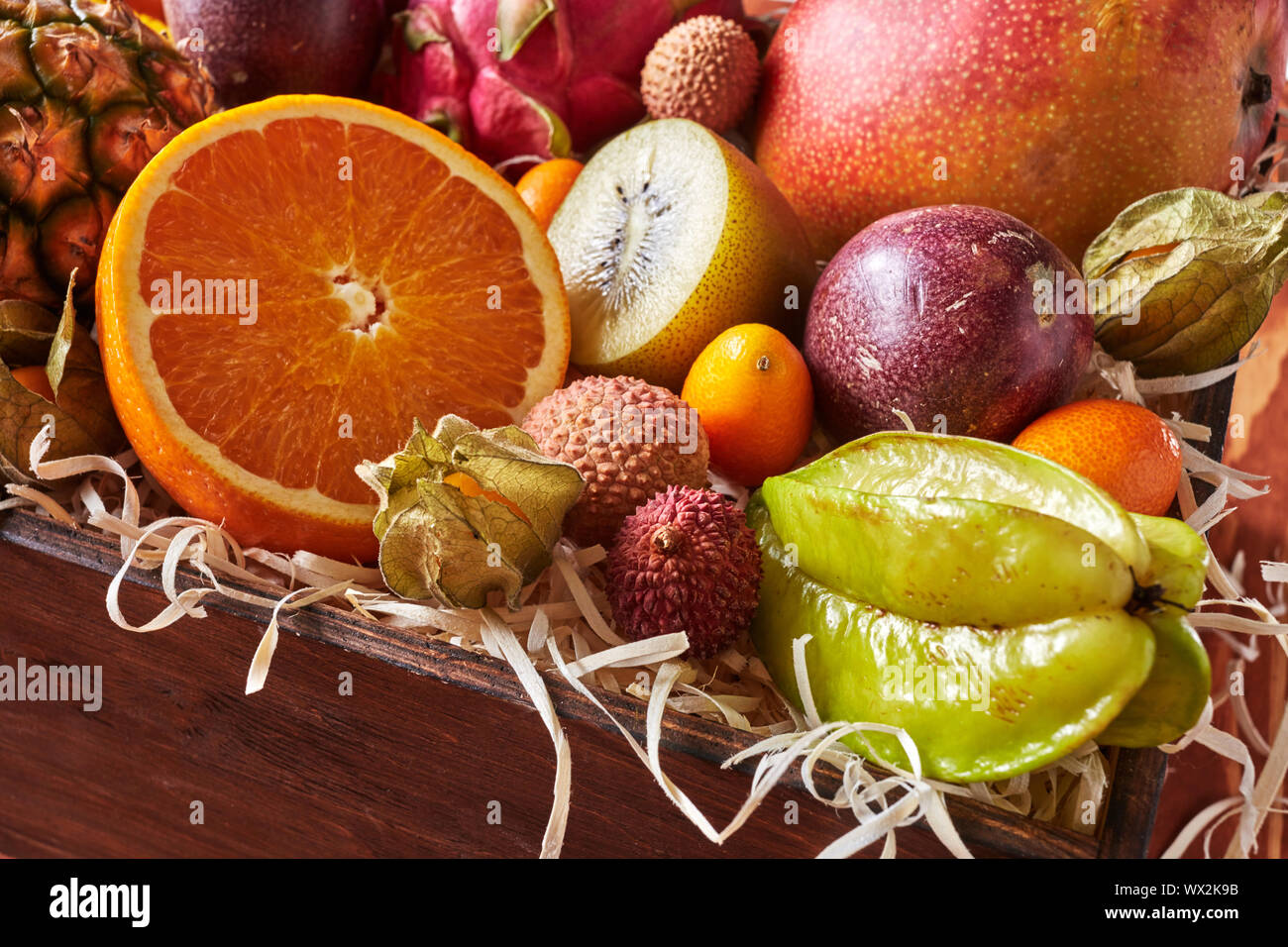 Close-up Box mit Gesunde frische Früchte Karambole, halb Orange, Kiwi, Pitahaya, Passionsfrucht, kumquat auf hölzernen Tisch. Stockfoto