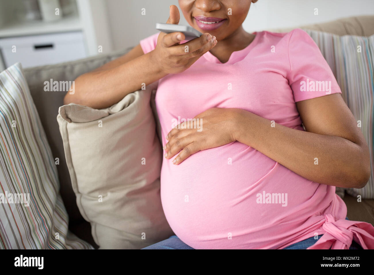 Schwangere Frau mit Voice-Recorder auf smartphone Stockfoto