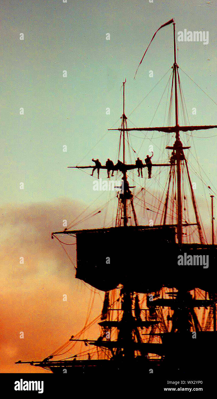 Eine silhouette Foto von Matrosen arbeiten an der Takelage eines modernen Segelschiff (Abschleppen/Senken der Segel) während des Abends während des Besuchs des Bemühen, Whitby, Yorkshire, England im Jahr 2000. Stockfoto