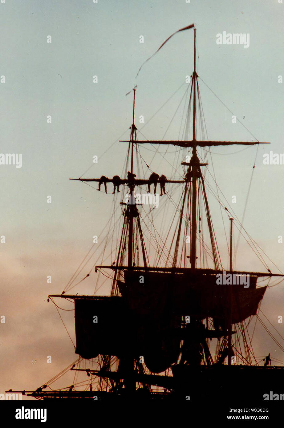 Eine silhouette Foto von Matrosen arbeiten an der Takelage eines modernen Segelschiff (Abschleppen/Senken der Segel) in der Dämmerung während des Besuchs des Bemühen, Whitby, Yorkshire, England im Jahr 2000. Stockfoto