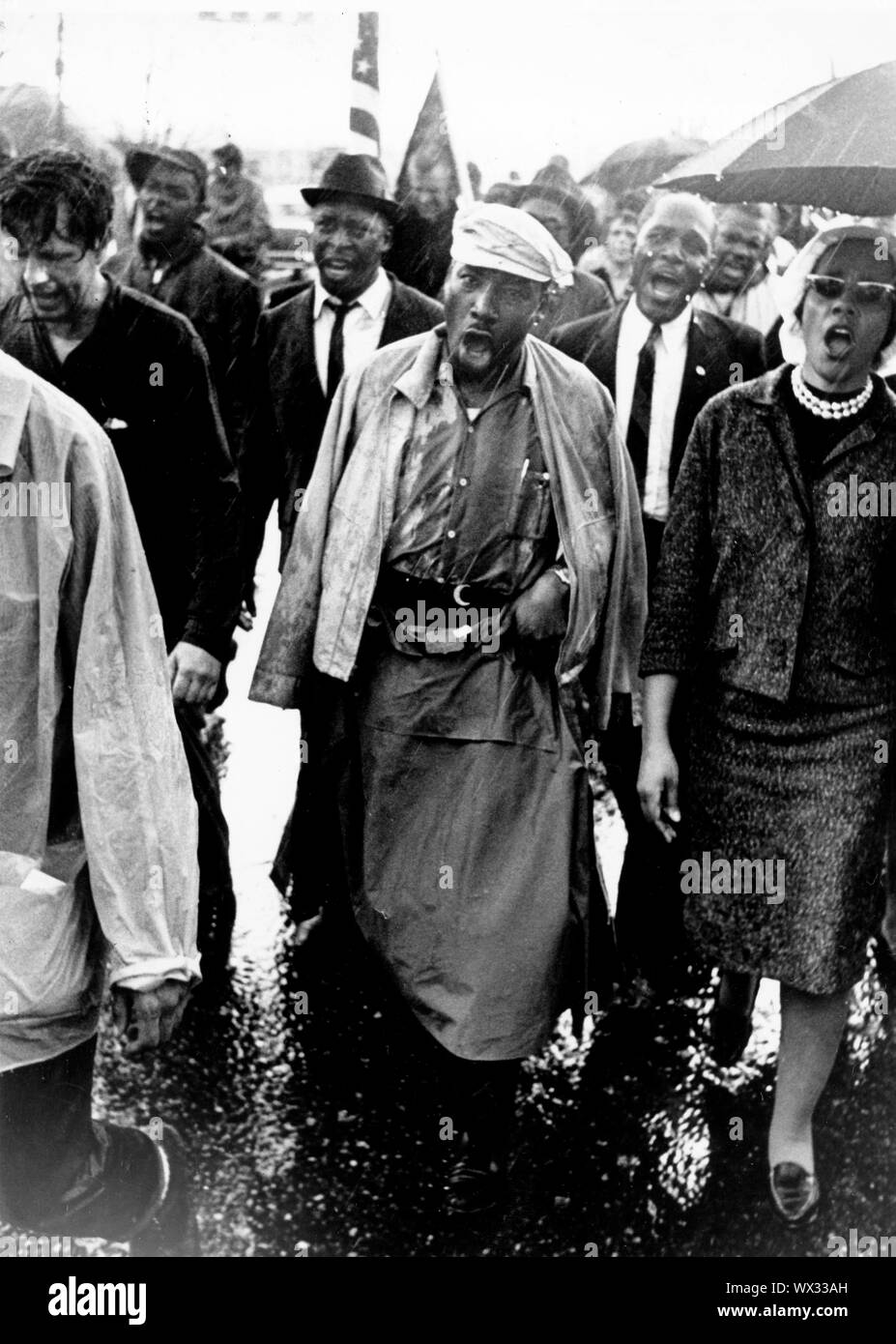 März 24, 1965 - Alabama, USA - American Civil Rights leader Dr. Martin Luther King jr., Mitte, und seine Frau Coretta Scott King, rechts, Singen, zusammen mit anderen, wie sie durch den Regen während der Selma nach Montgomery März für Stimmrechte zu Fuß. Früher Märsche hatte aufgehört, die erste gewaltsam von der Polizei und Nationalgardisten. Im März dieses Jahres war unter dem Schutz der föderativ bestellt der Nationalgarde abgeschlossen. Rund 3200 Menschen links Selma am März 21. und mit der Zeit erreichten sie Montgomery die Aktivisten Masse auf 25.000 angewachsen war. (Bild: © Keystone Presse Agentur/Keystone USA über Stockfoto