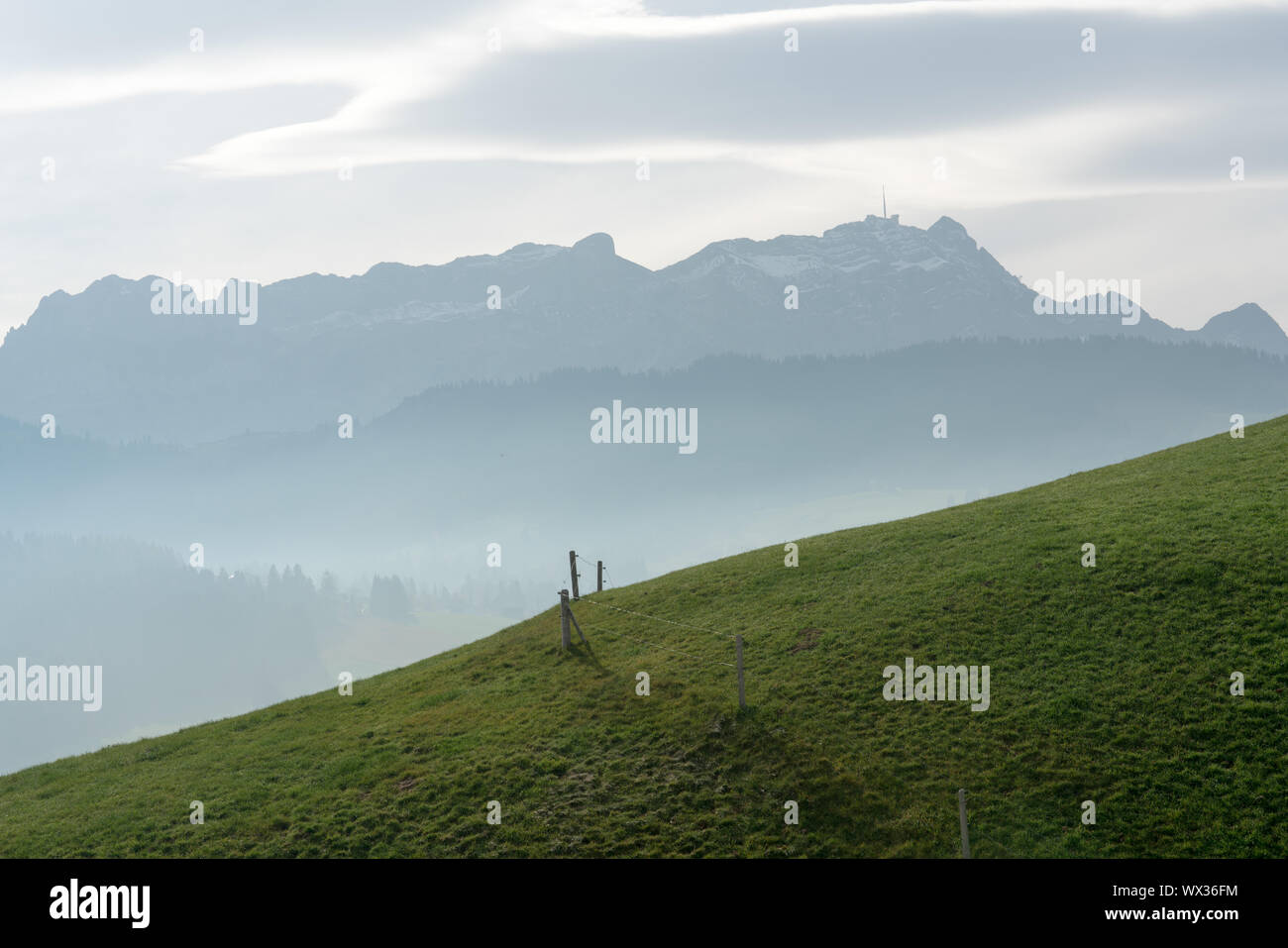Idyllische und ruhige Berglandschaft mit einem Holzzaun auf einem grasbewachsenen Hügel und eine großartige Aussicht Stockfoto
