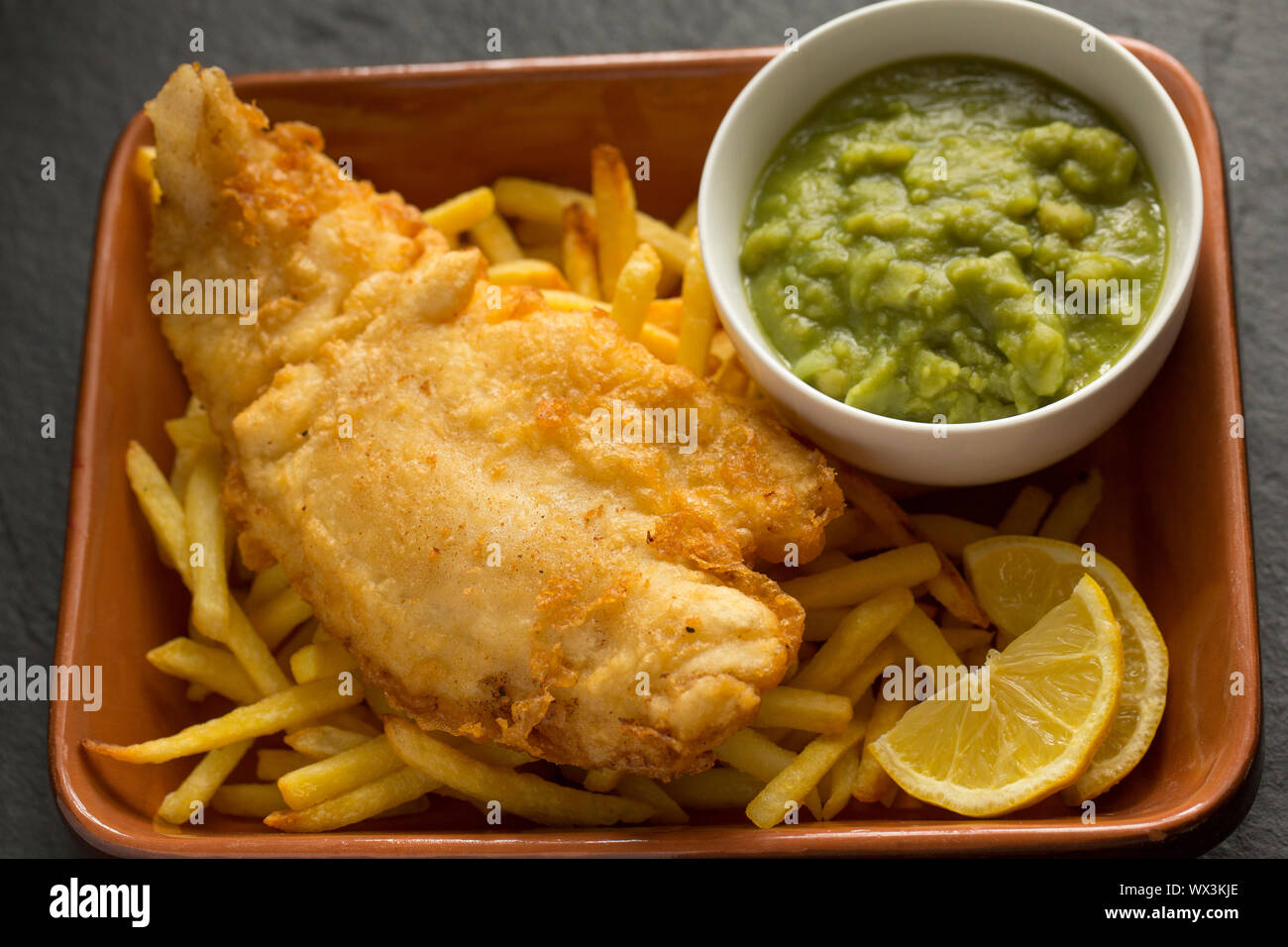 Ein hausgemachtes Filet von der Linie gefangen Pollack Pollachius pollachius, die in Teig getaucht vor dem Frittieren und Servieren mit Backofen Chips und Stockfoto