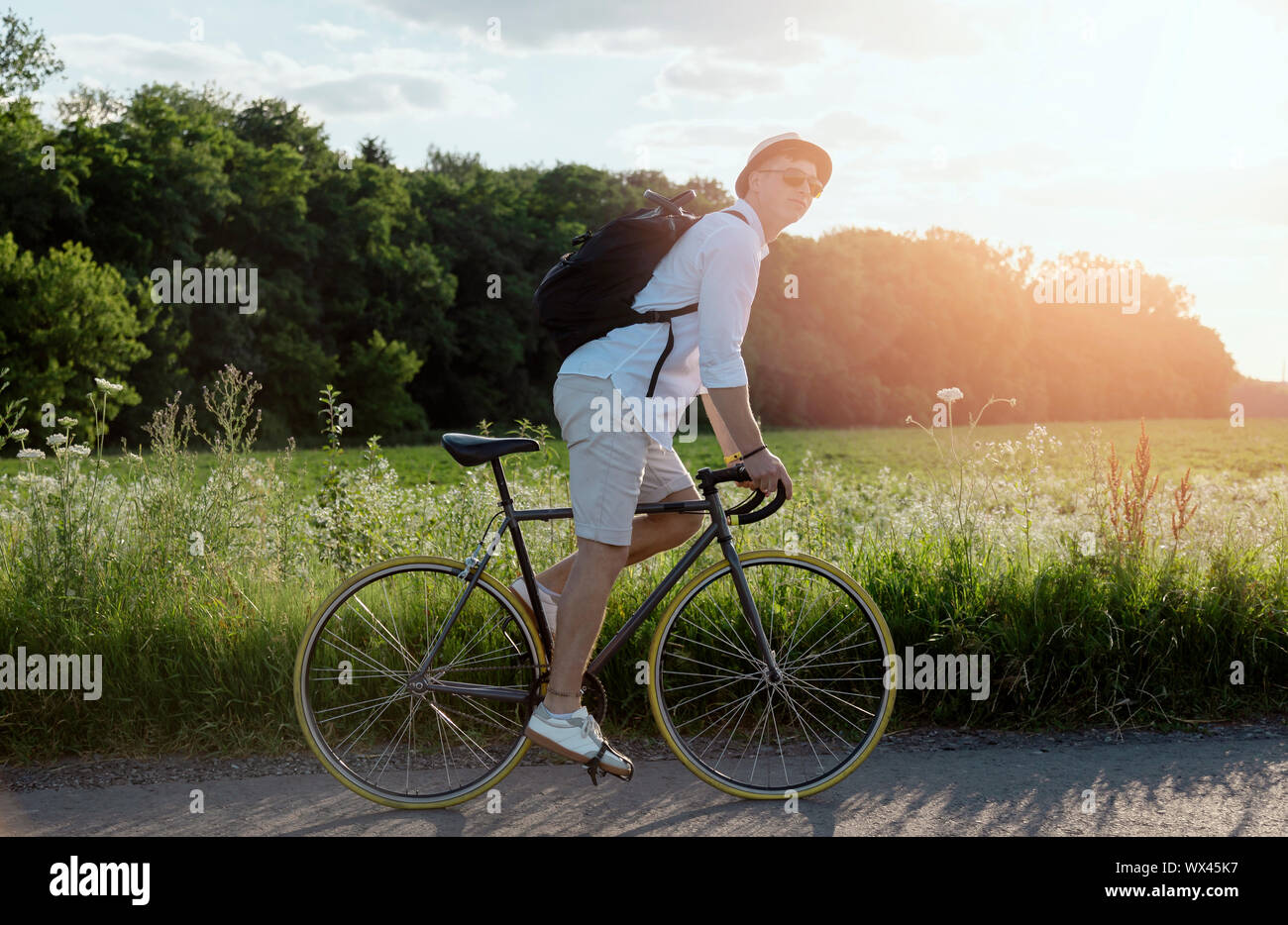 Junge Mann in Weiß mit Sonnenbrille seiner ländlichen Radtour genießen Stockfoto