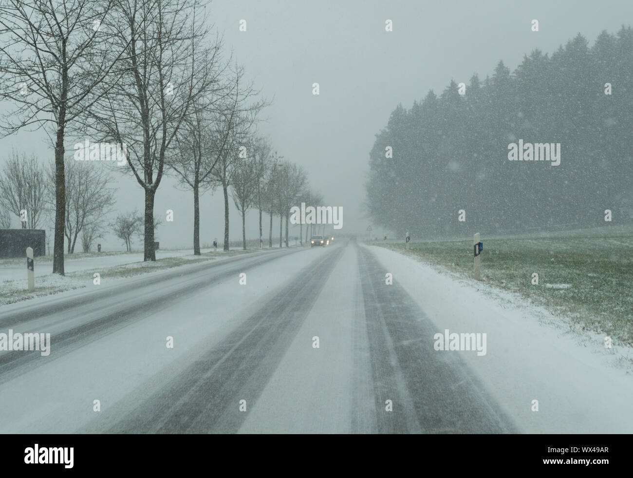 Schneesturm auf der Landstraße und gefährliche Straßenverhältnisse im Winter mit Autos fahren Stockfoto
