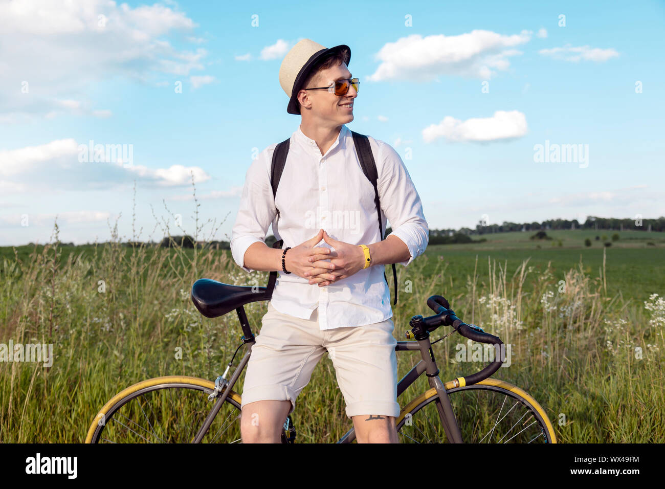 Junge ruhenden zufriedene Radfahrer sitzt auf seinem Fahrrad während seiner Stopp auf einer Landstraße Stockfoto