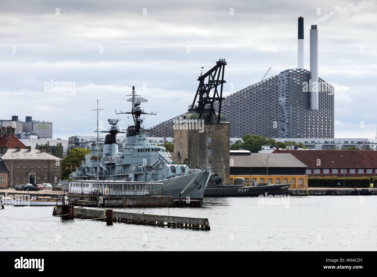 Ein kriegsschiff im Hafen von Amager, Kopenhagen, Dänemark, mit dem Amager Bakke Verbrennungsanlage und Skipiste im Abstand Stockfoto