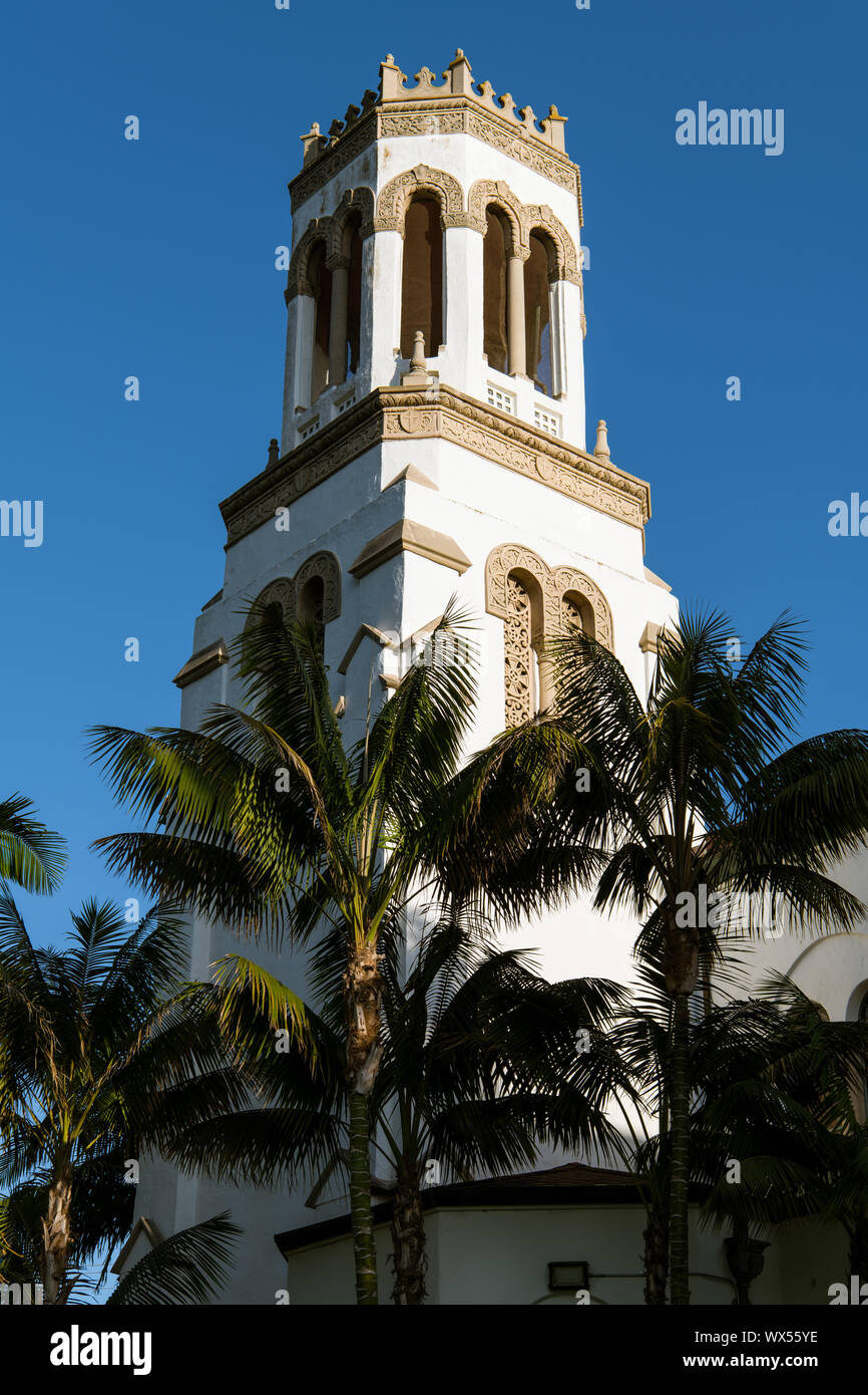 Die untergehende Sonne highlights eine Seite eines weißen Glockenturm und Palmen - der Schmerzhaften Muttergottes Kirche in Santa Barbara, Kalifornien Stockfoto