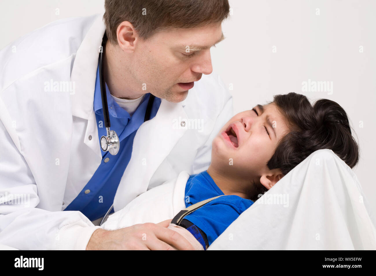 Männlicher Arzt Anfang der vierziger Jahre beruhigende fünf Jahre alte behinderte Patienten während Büro besuchen Stockfoto