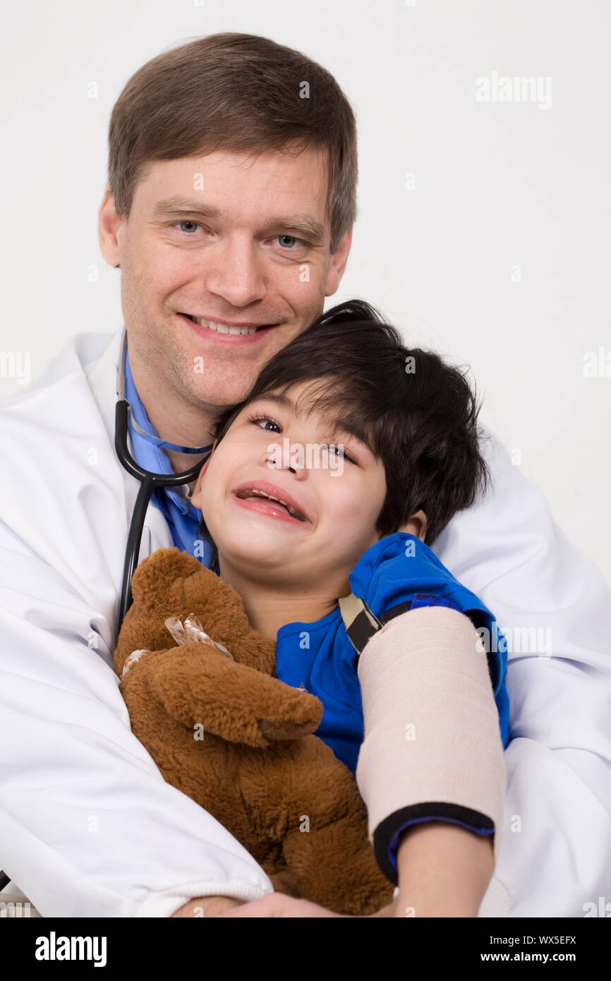 Männlicher Arzt Anfang der vierziger Jahre beruhigende fünf Jahre alte behinderte Patienten während Büro besuchen Stockfoto