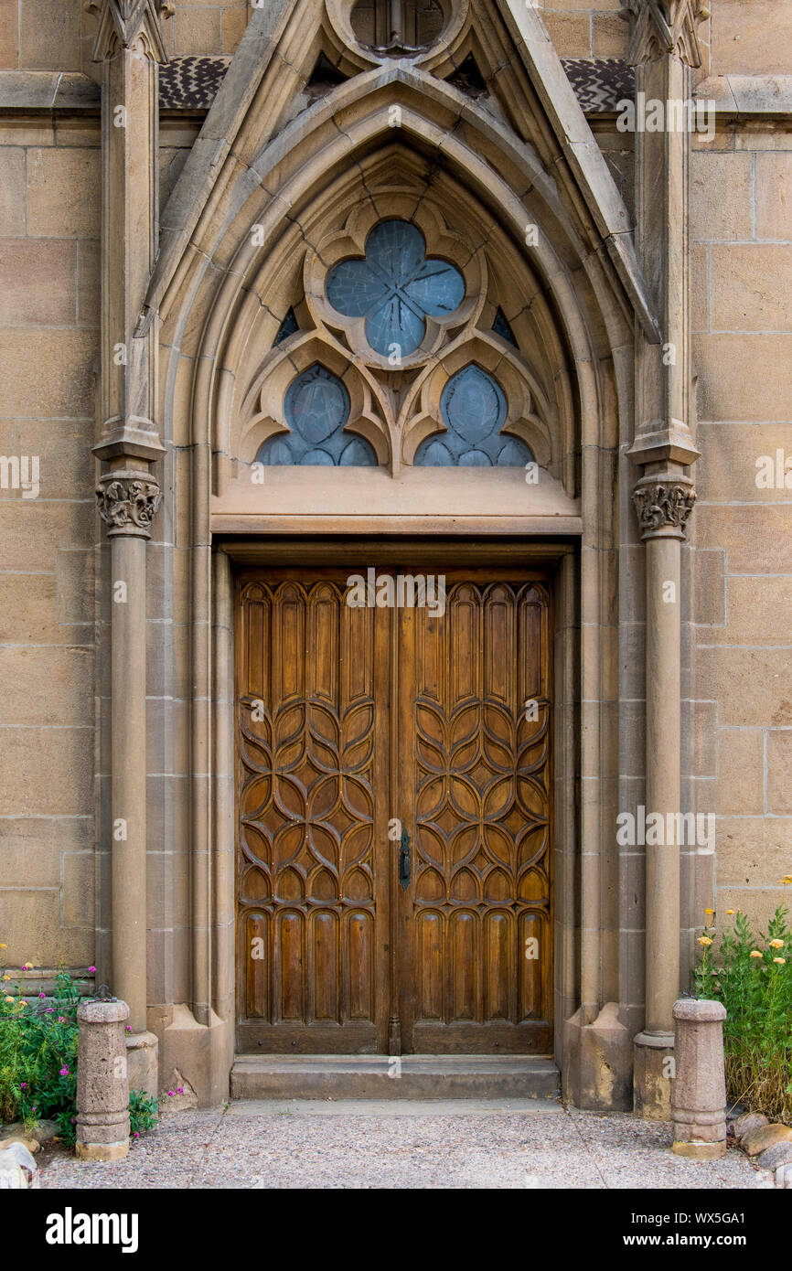 Rustikale verzierten Holztür in einem gotischen Architektur Fassade eines alten Kirche - Loretto Kapelle in Santa Fe, New Mexico Stockfoto