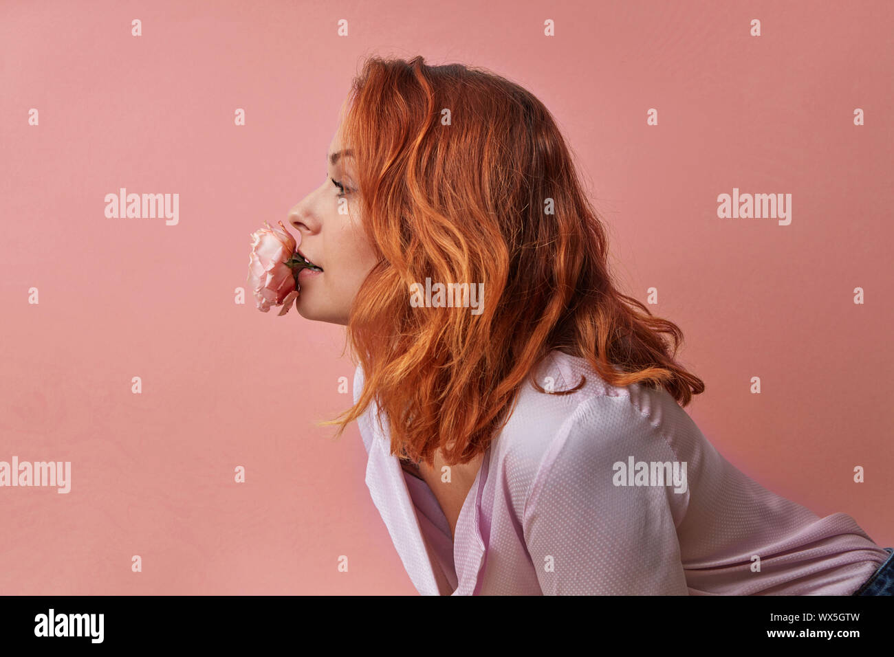 Studio Fashion Foto der schöne junge Frau mit Blumen in den Mund auf einem Hintergrund in einer Farbe in einer Farbe des Jahres 2019 L Stockfoto