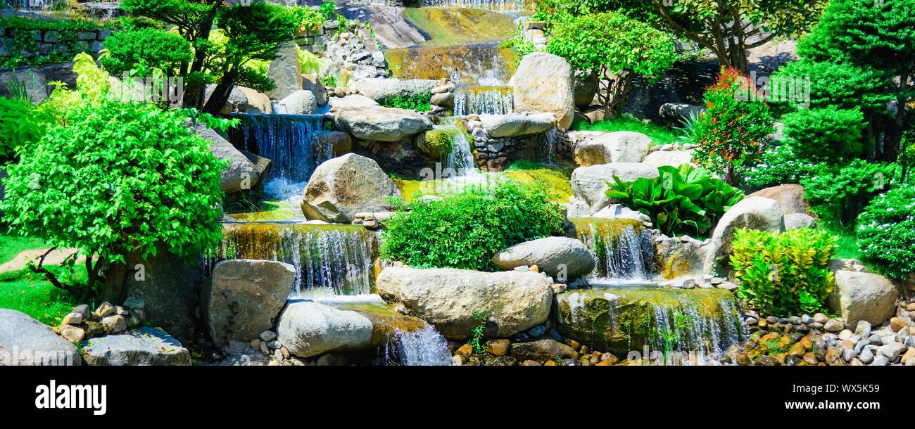 Künstlicher Wasserfall vegetation Steine Stockfoto