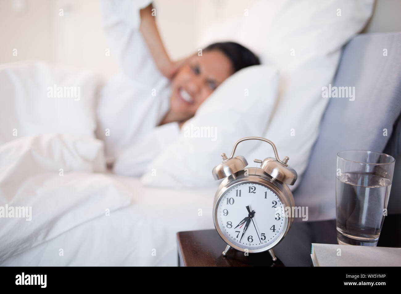 Wecker, junge Frau, die ihre Ohren Stockfoto