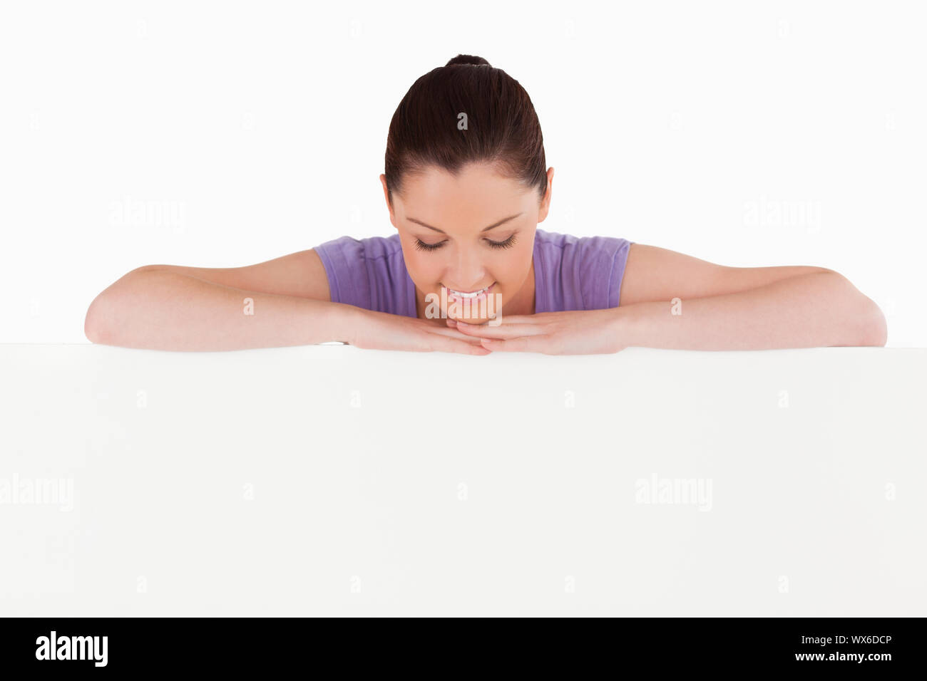 Schöne Frau posiert hinter einer Anschlagtafel beim Stehen vor einem weißen Hintergrund Stockfoto