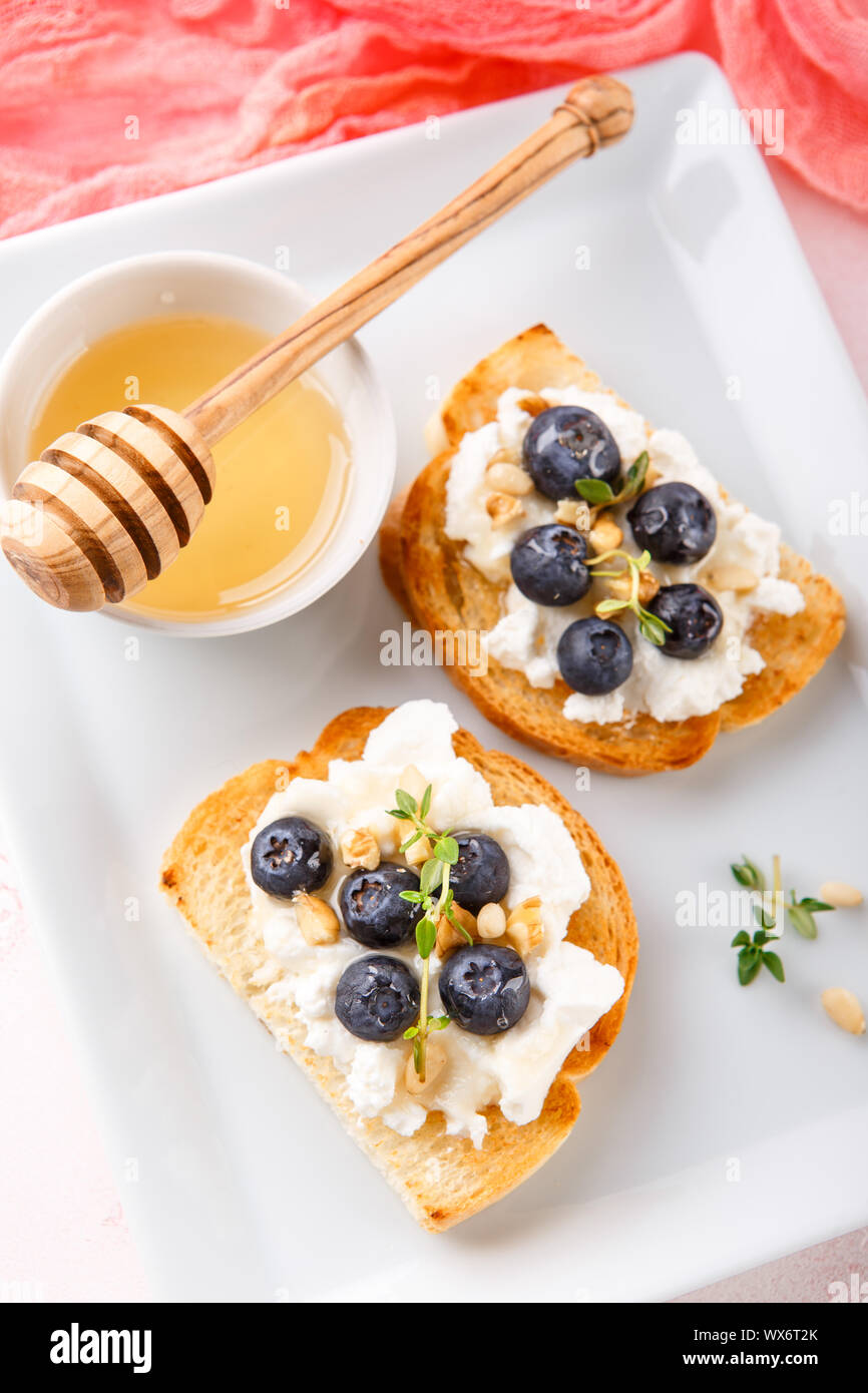 Toast mit frischen Beeren Heidelbeeren Ricotta, Thymian, Honig und Haselnüssen, serviert. Stockfoto