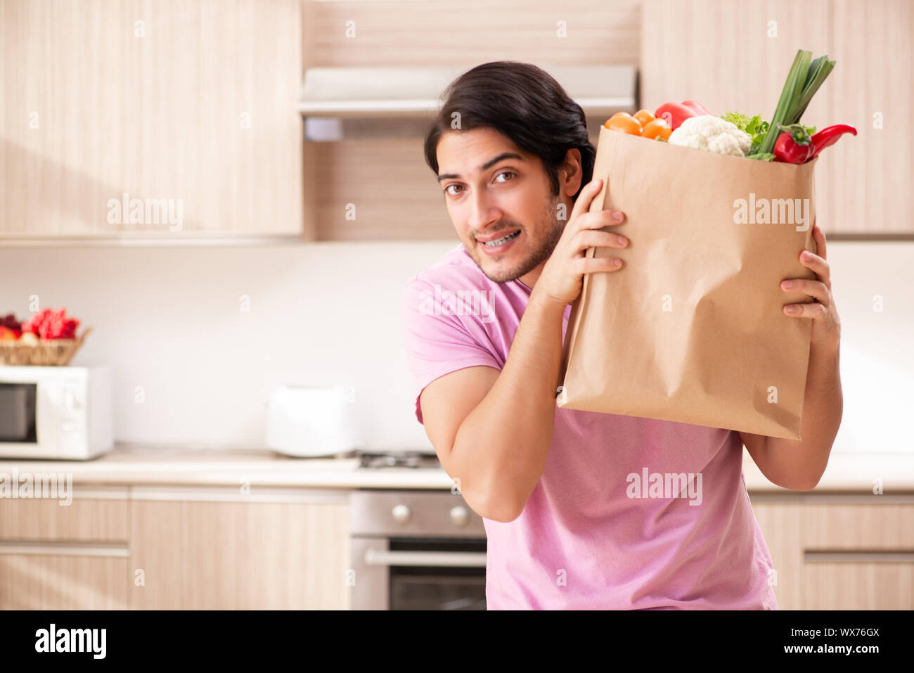 Junger stattlicher Mann mit Gemüse in der Küche Stockfoto