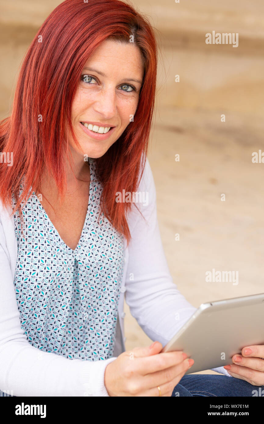 Porträt eines hübschen Lächeln rothaarige Frau liest Informationen über die Touch Pad Stockfoto