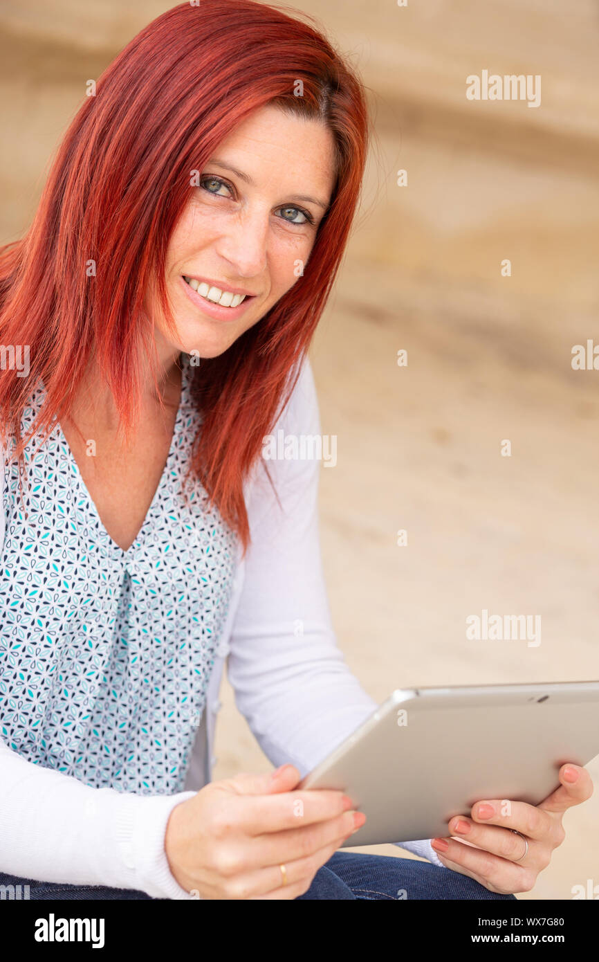 Porträt eines hübschen Lächeln rothaarige Frau liest Informationen über die Touch Pad Stockfoto