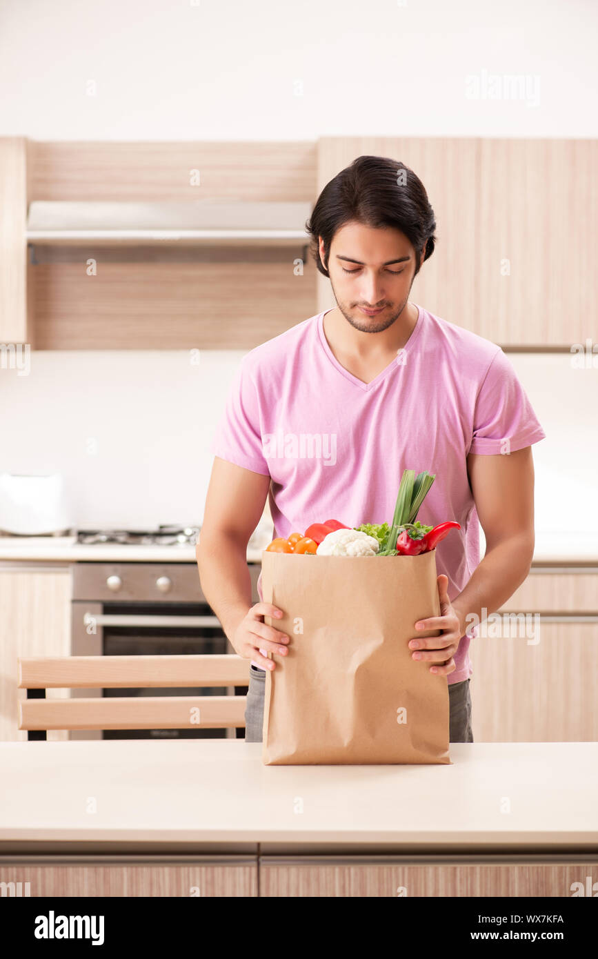 Junger stattlicher Mann mit Gemüse in der Küche Stockfoto