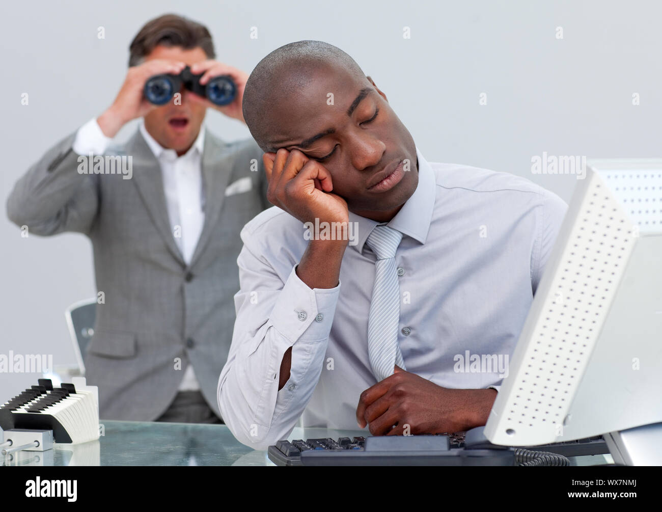 Schlafend Geschäftsmann von einem Mann auf der Suche durch ein Fernglas im Büro gestört Stockfoto