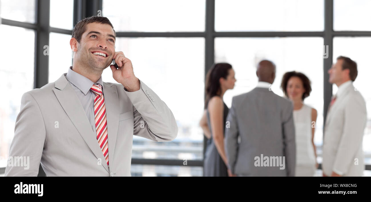 Charismatischen Geschäftsmann am Telefon im Büro mit seinem team Stockfoto