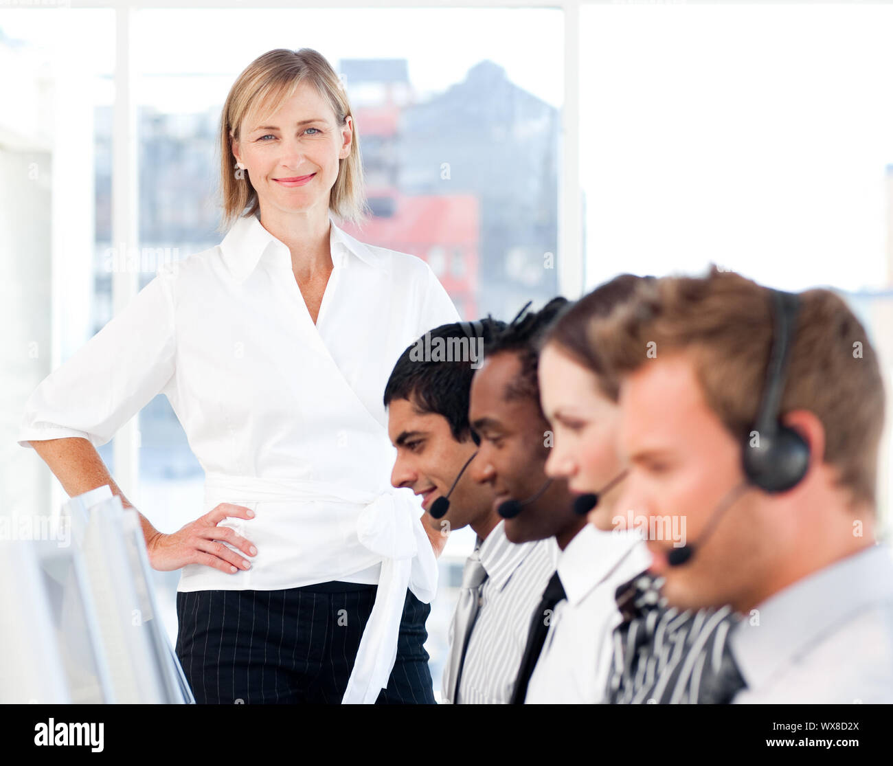 Helle weibliche Führer ihr konzentriertes Team, das in einem Call Center Stockfoto