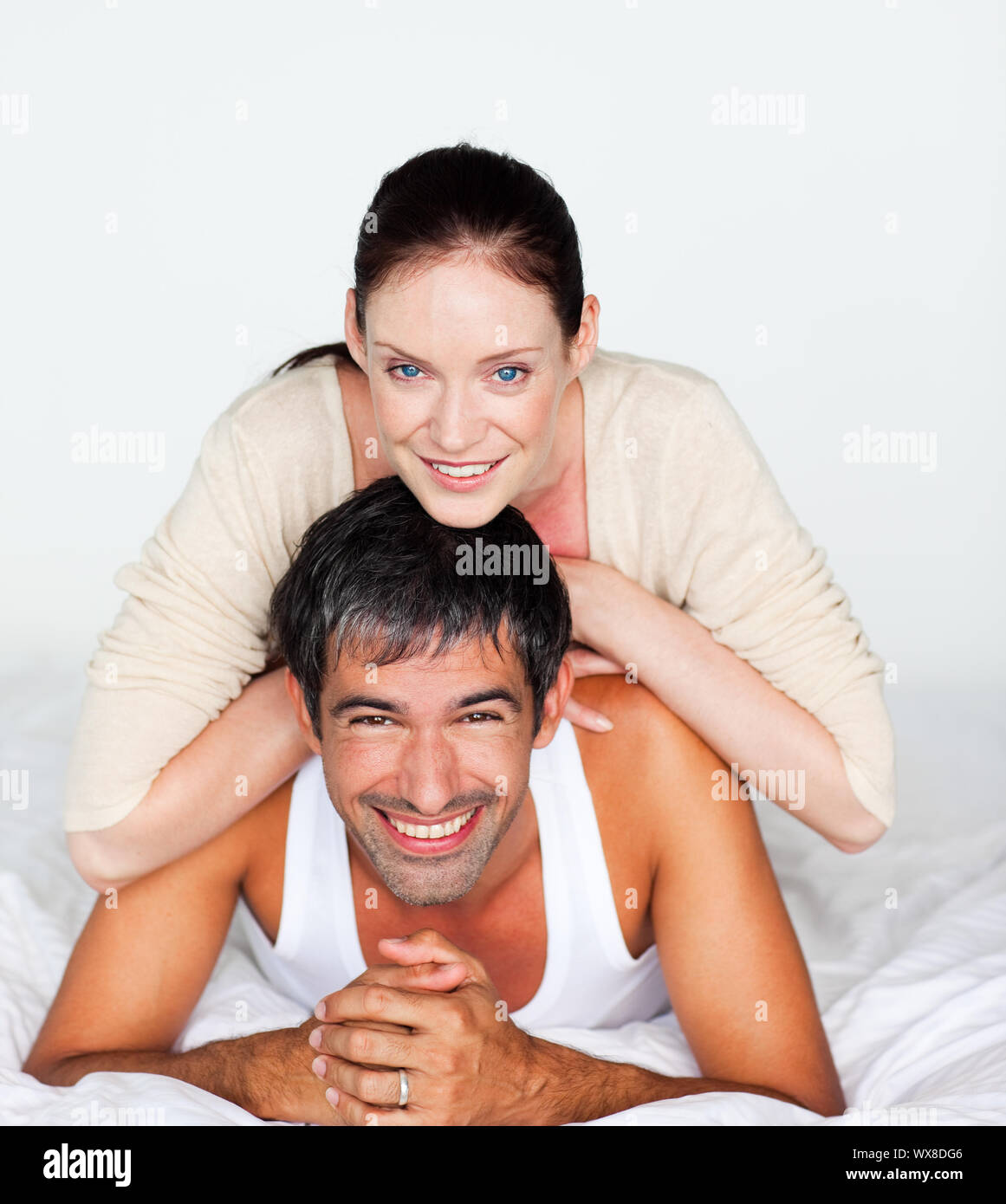 Fröhliches paar auf einem weißen Bett liegend Stockfoto