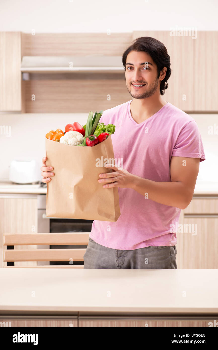 Junger stattlicher Mann mit Gemüse in der Küche Stockfoto