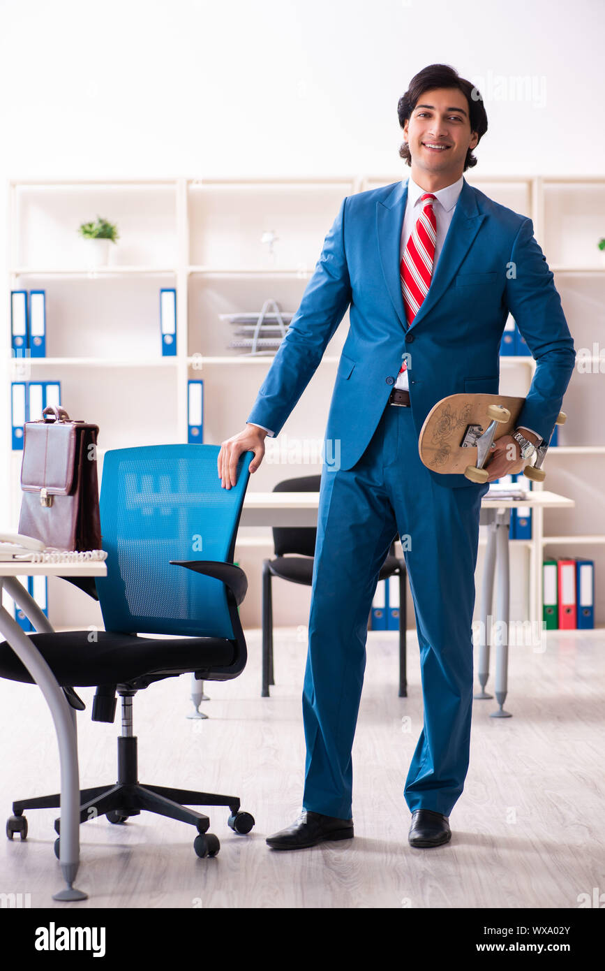 Junge gut aussehender Geschäftsmann mit Longboard im Büro Stockfoto