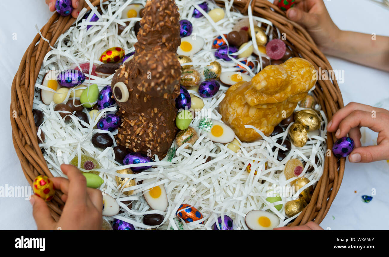 Viele Kinder Hände für Süßigkeiten Süßigkeiten und Schokolade in ein Osterei Warenkorb Ostern Stockfoto