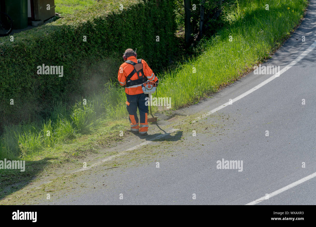 Stadt Wartung Arbeiter schneiden Unkraut auf der Straße Schulter mit einem Trimmer Stockfoto