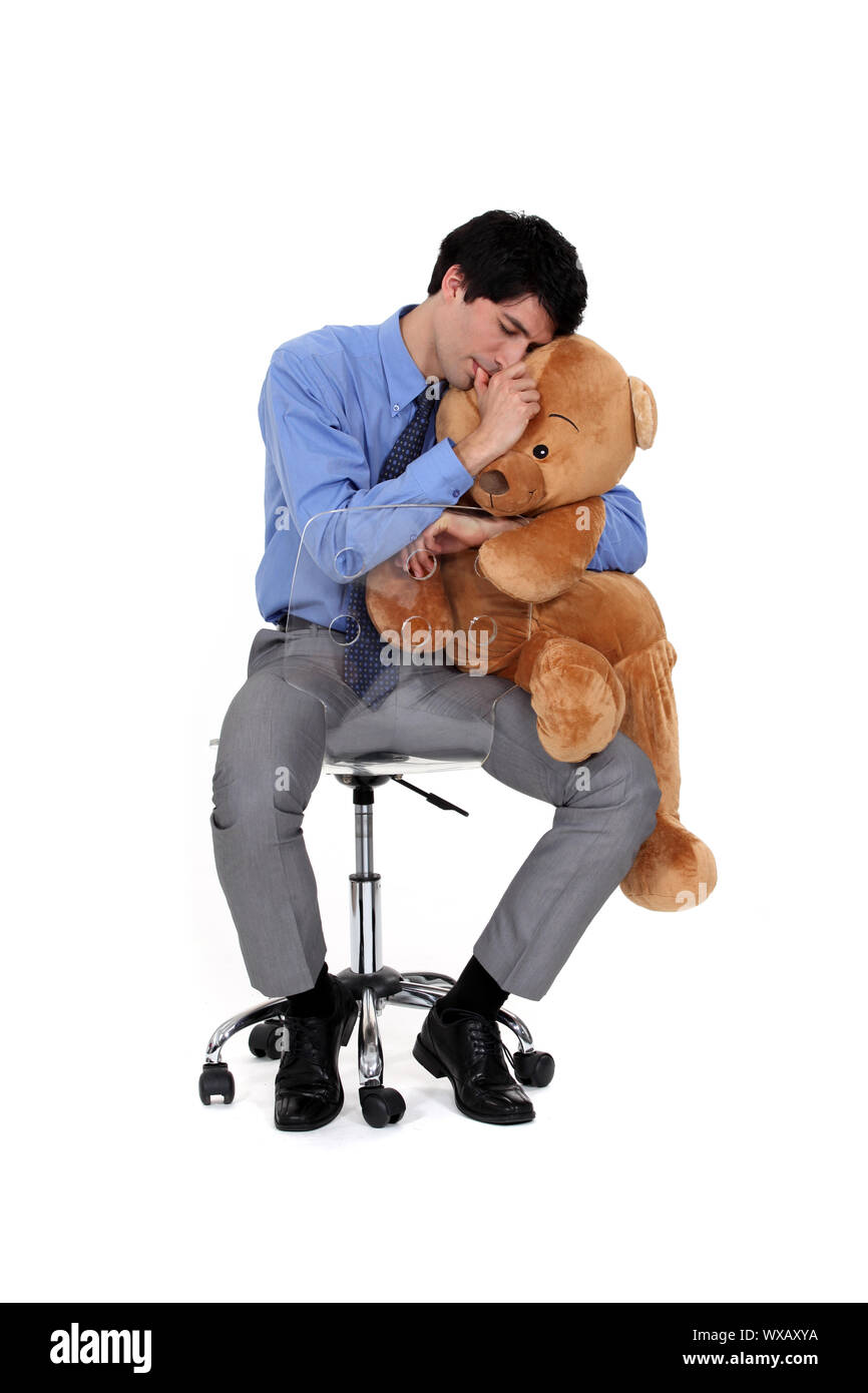 Ein Erwachsener Geschäftsmann umarmt einen großen Teddybär. Stockfoto