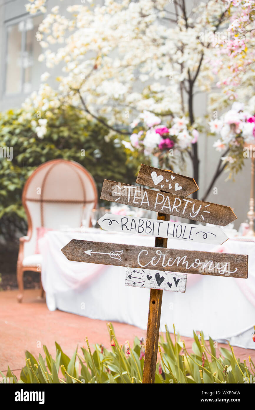 Wegweiser zeigen Richtungen für Alice im Wunderland Hochzeit im Frühling mit blühenden weißer Hartriegel und ein Bankett Tisch themed Stockfoto