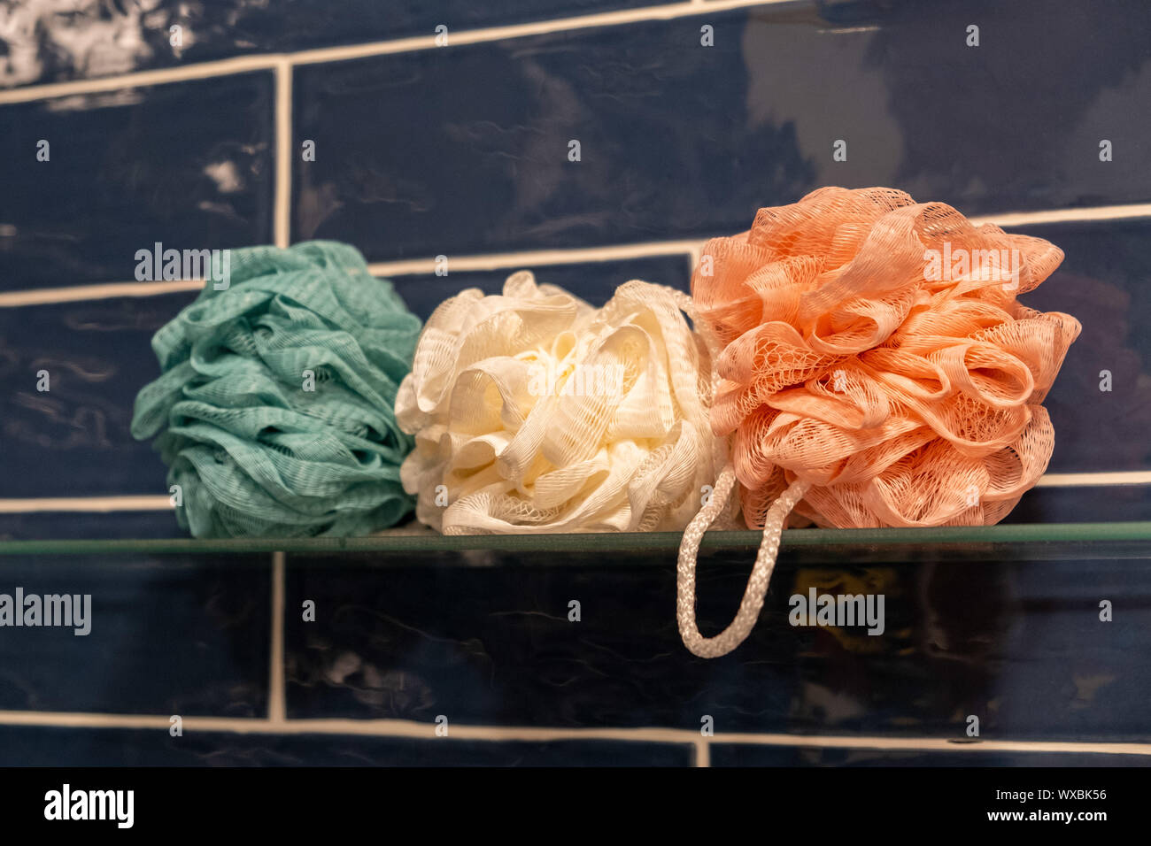 Bunte Badewanne Dusche Schwämme auf Glas Regal im Badezimmer Stockfoto