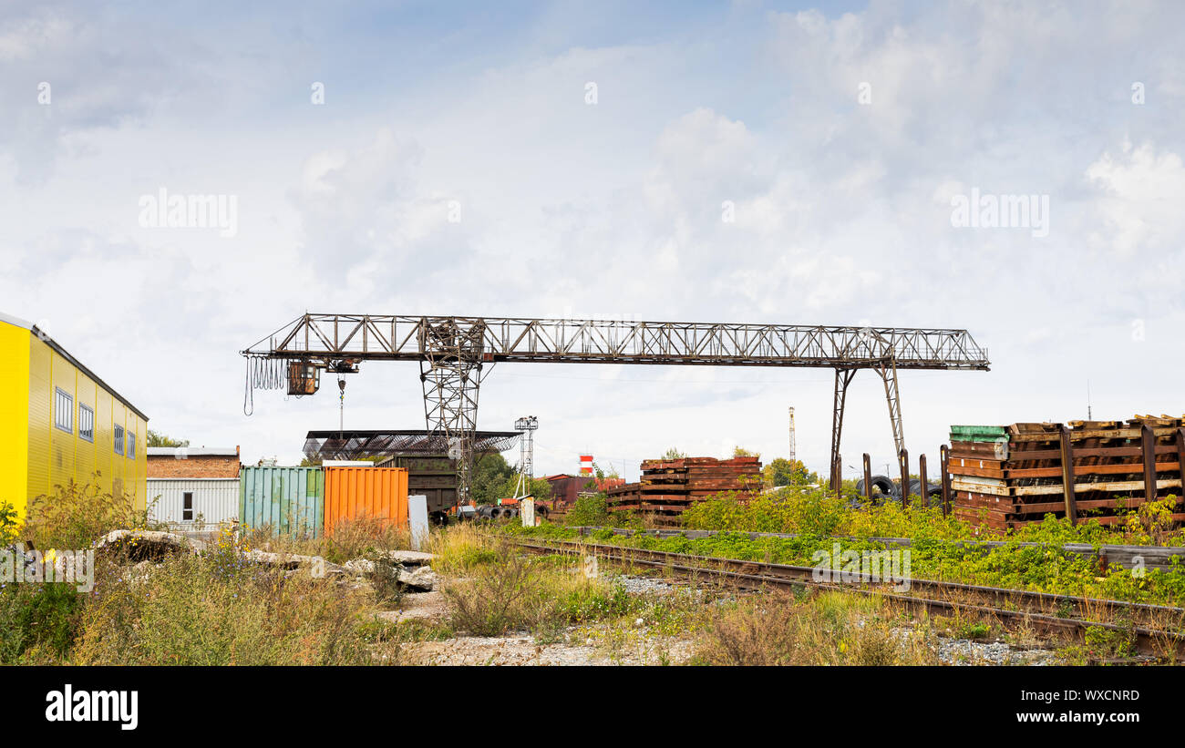 Große metal Gantry Kran auf der Baustelle, im Hintergrund Industriehallen für die Lagerung von Waren. Art der Lagerung metall Strukturen der Gantry Stockfoto