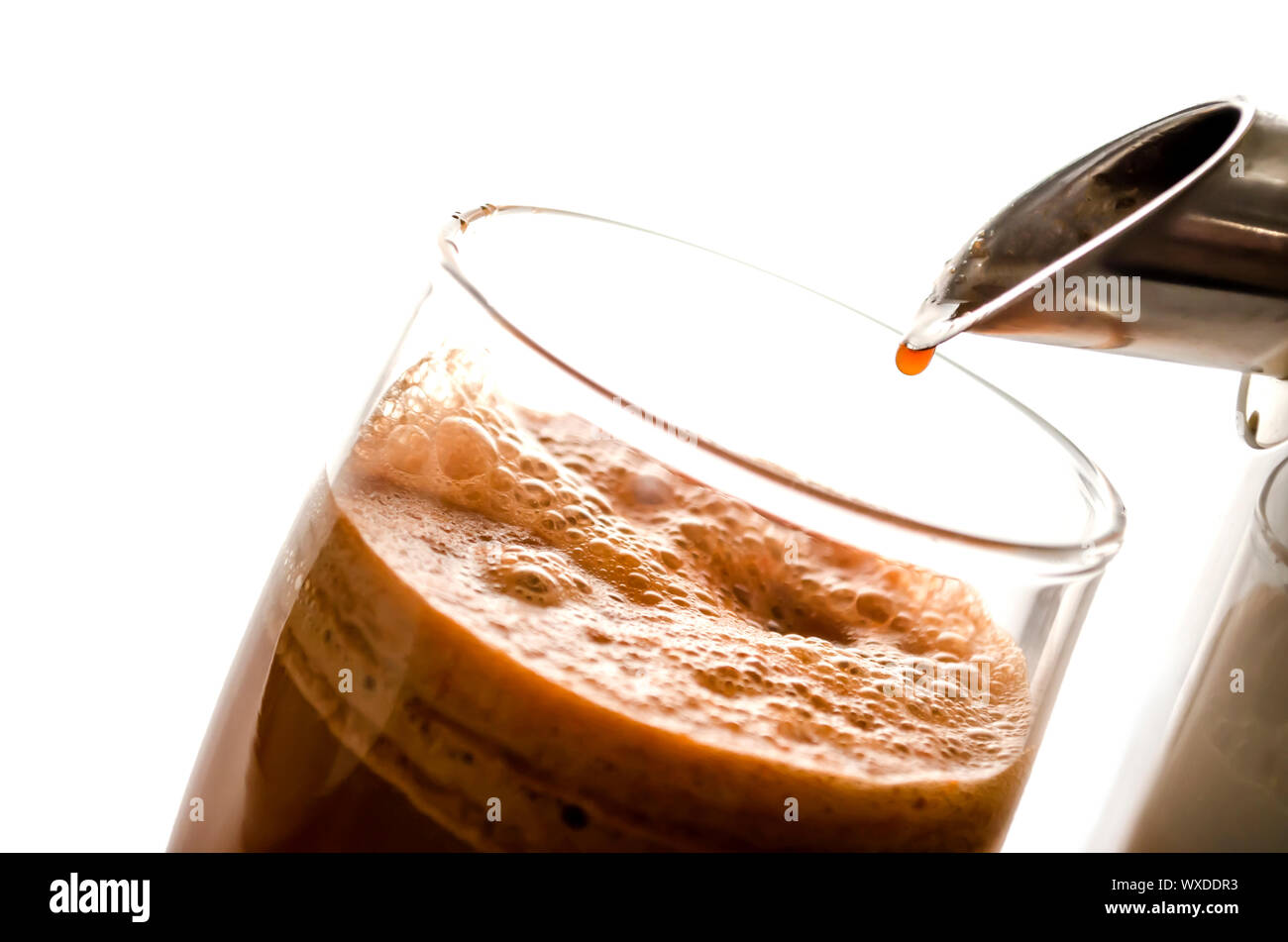 Nahaufnahme von frisch gepresster Karottensaft mit einem Entsafter. Auf einem weißen Hintergrund. Stockfoto