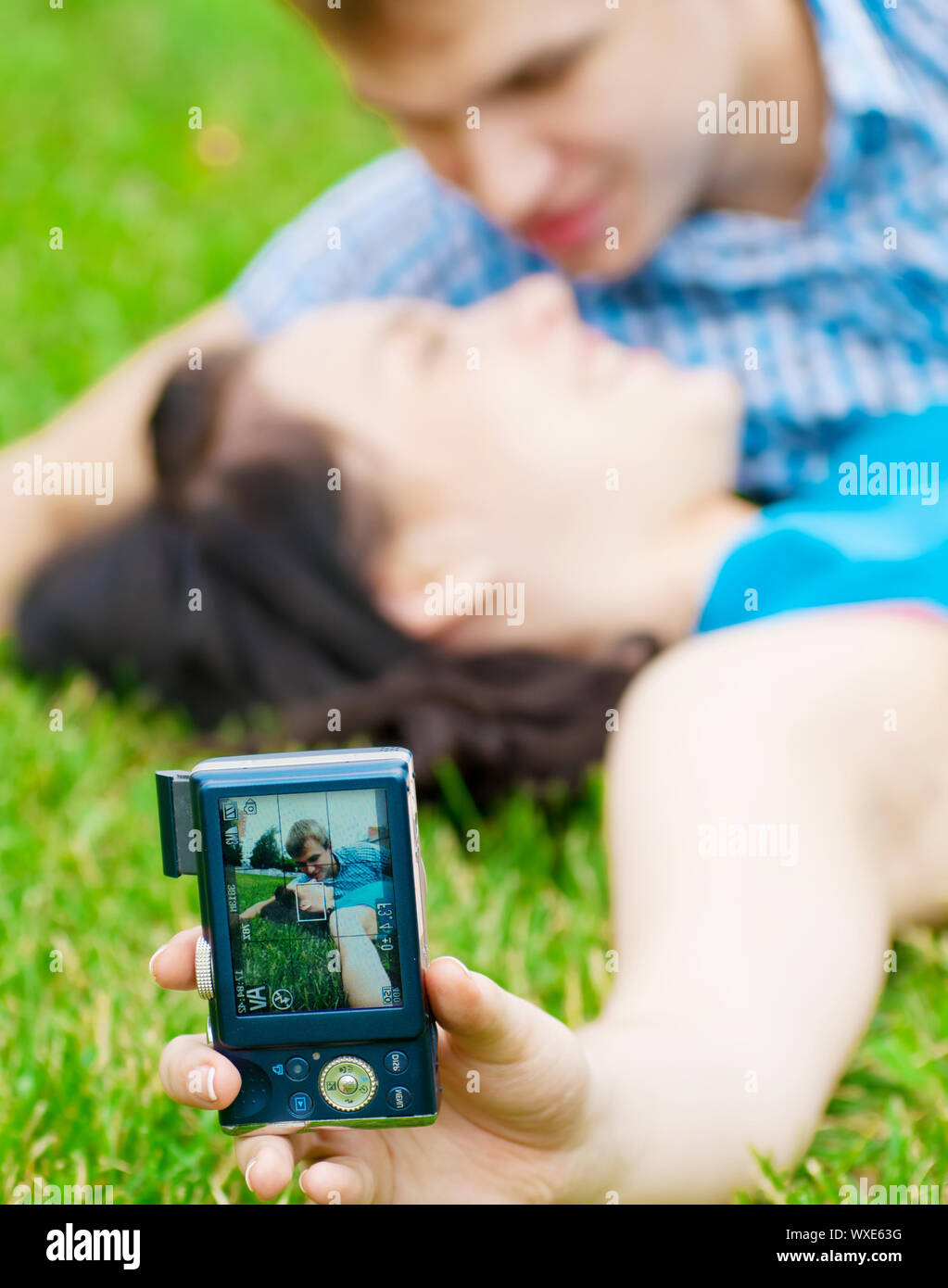 Junge emotionale Happy teenage Paar unter Bild auf Gras im City Park Stockfoto