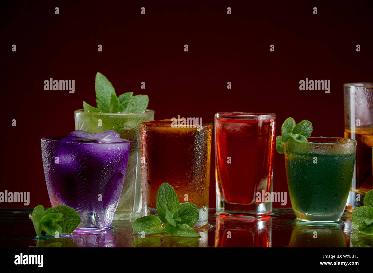 Satz von alkoholischen Cocktails mit Eis und Minze auf rotem Hintergrund Stockfoto