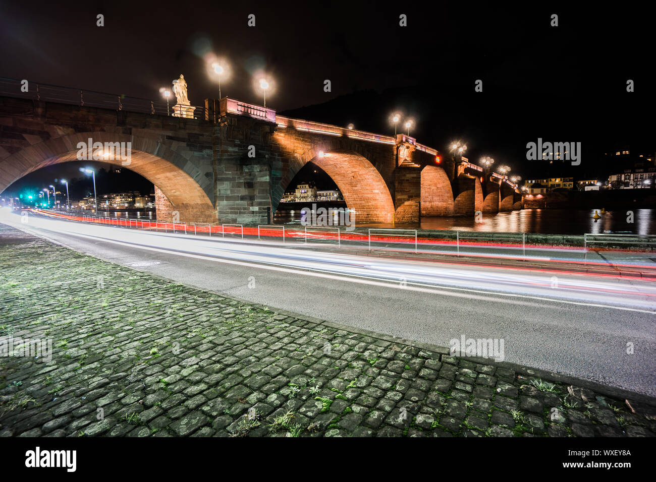Straße und der Neckar mit alten Heidelberg Bridge bei Nacht Stockfoto