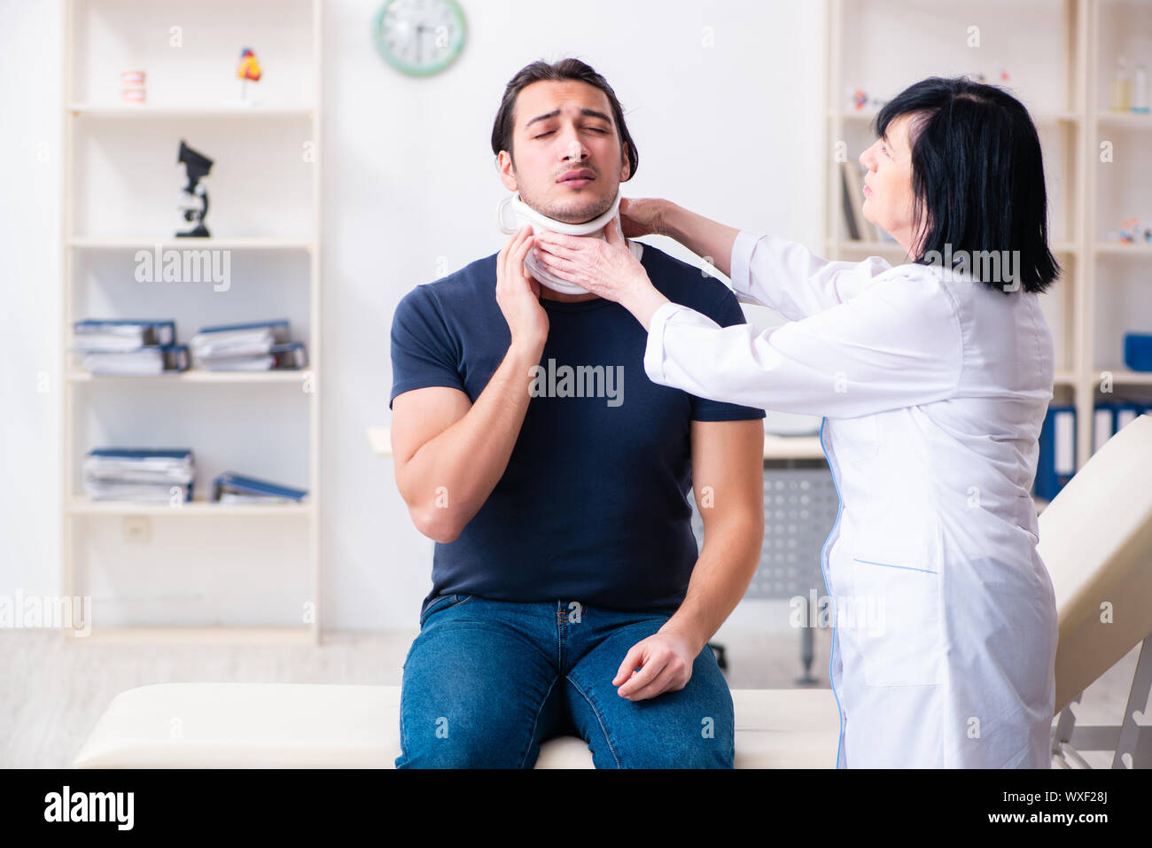 Junge männliche Patienten im Alter besuchen Ärztin Stockfoto