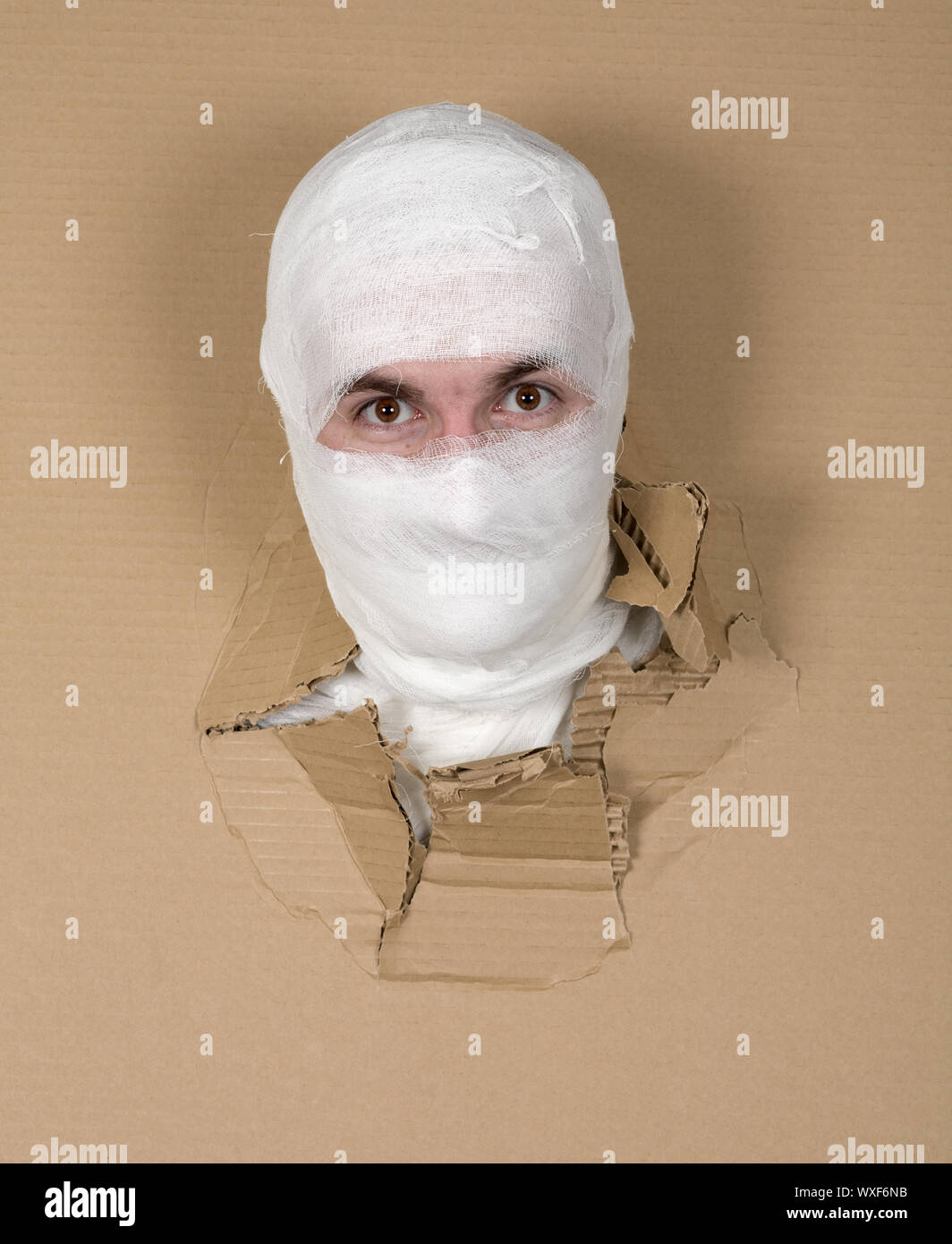 Mann im Kostüm Mumie durch Loch im Karton Stockfoto