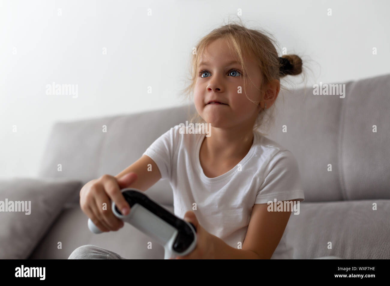 Wettbewerbsfähige Mädchen spielen mit Gamepad auf der Couch Stockfoto