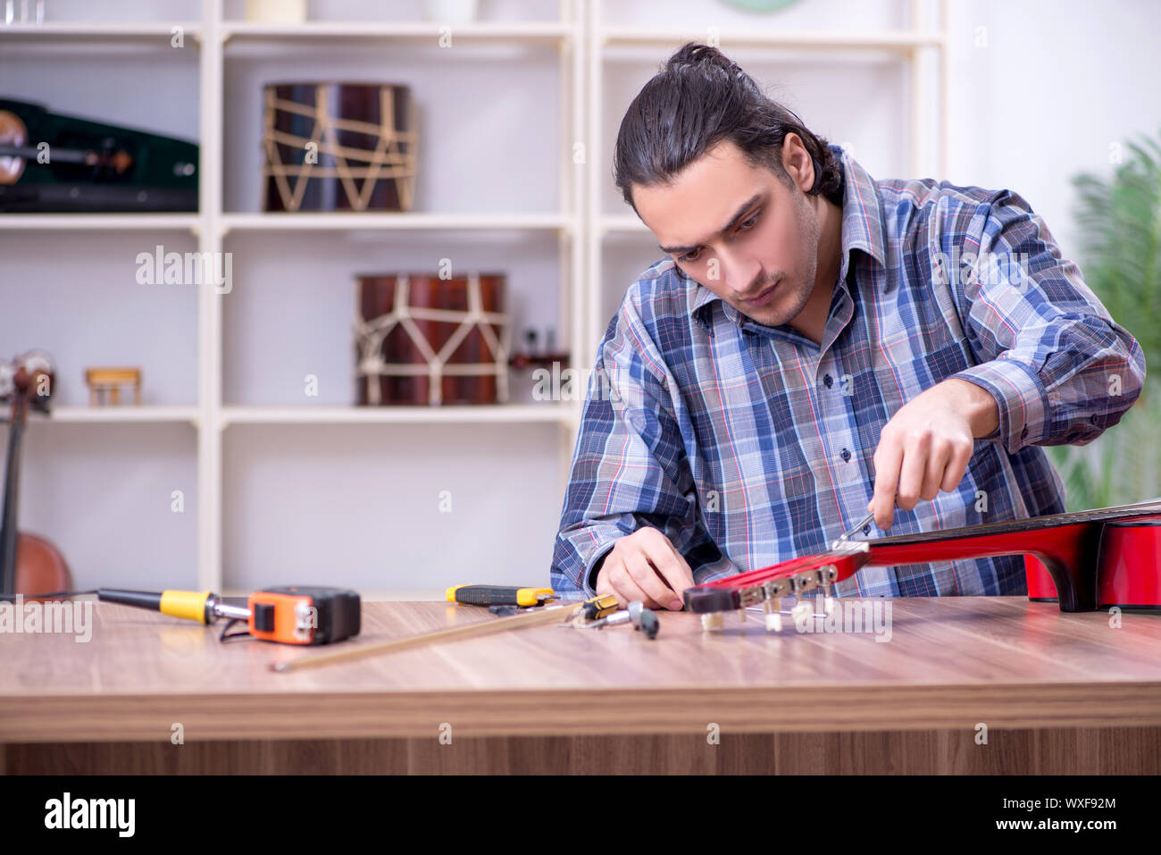 Junge schöne Handwerker Reparatur Gitarre Stockfoto