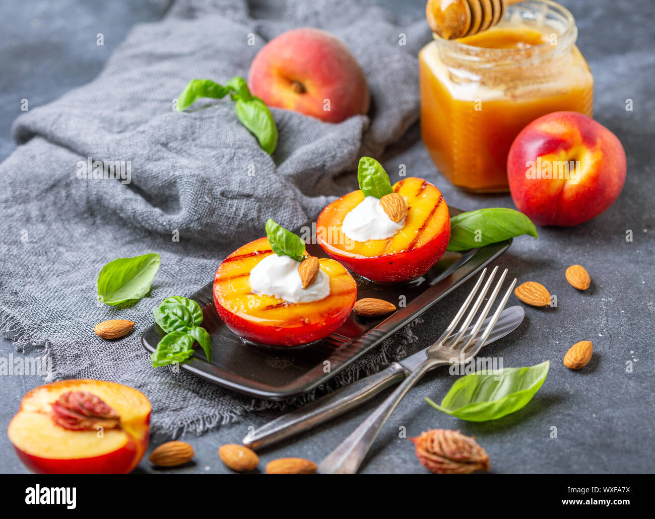 Gegrillte Pfirsiche mit Joghurt, Honig und grüne Basilikum. Stockfoto