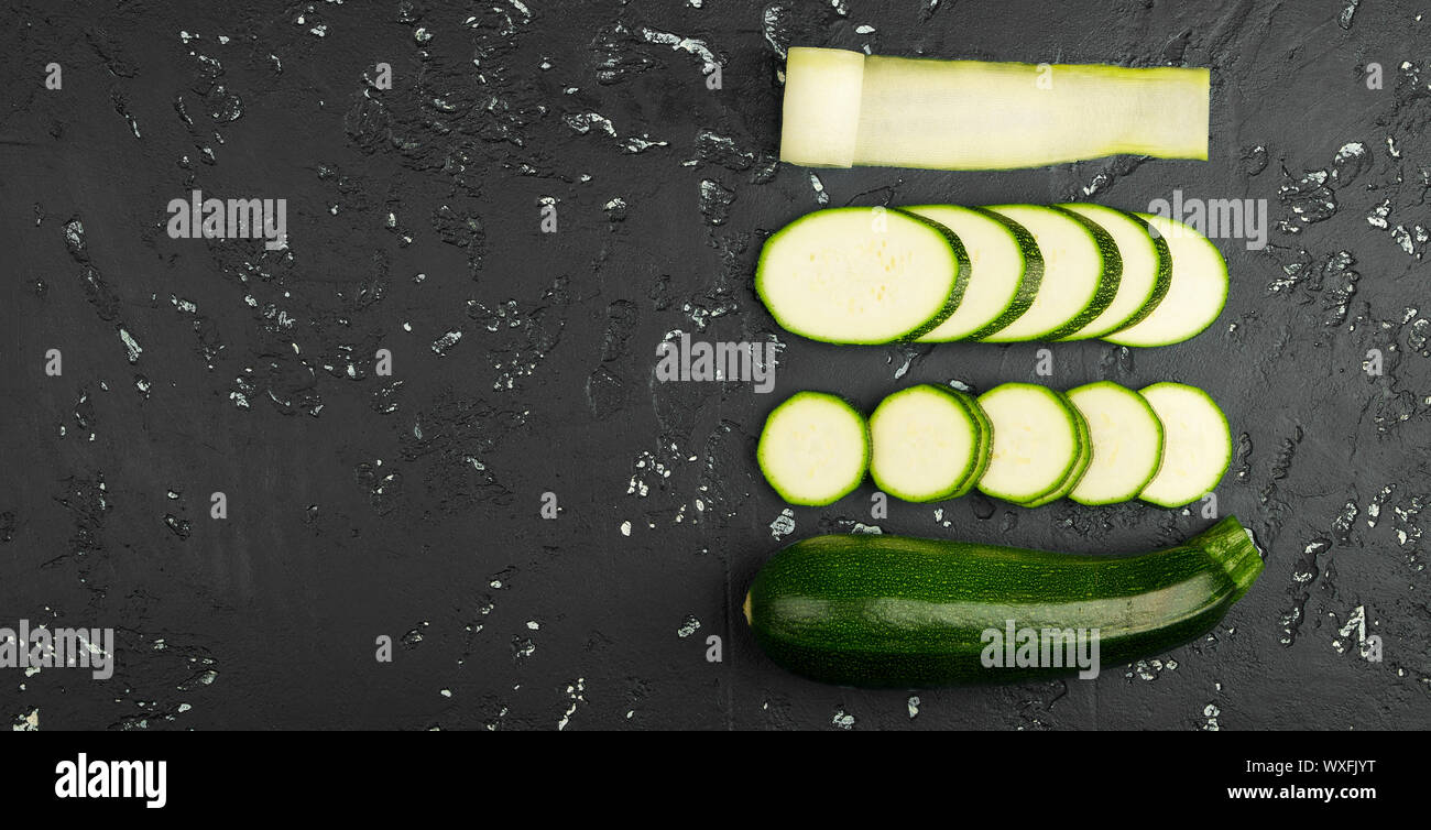 Frische grüne Zucchini auf einen dunklen Tisch. Die Aussicht von oben. Kopieren Sie Platz. Stockfoto