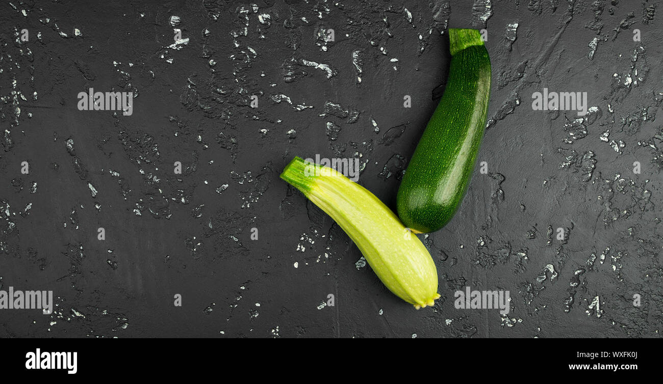 Frische grüne Zucchini auf einen dunklen Tisch. Die Aussicht von oben. Kopieren Sie Platz. Stockfoto