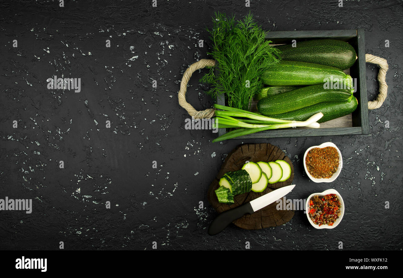 Frische grüne Zucchini auf einen dunklen Tisch. Die Aussicht von oben. Kopieren Sie Platz. Stockfoto