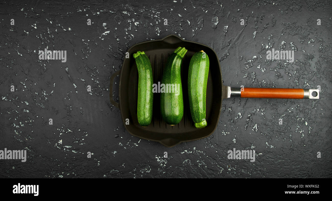 Frische grüne Zucchini auf einen dunklen Tisch. Die Aussicht von oben. Kopieren Sie Platz. Stockfoto